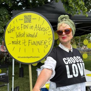 Hilary holding a hand drawn sign saying 'What makes Abbey FUN? What would make it FUNNER?'